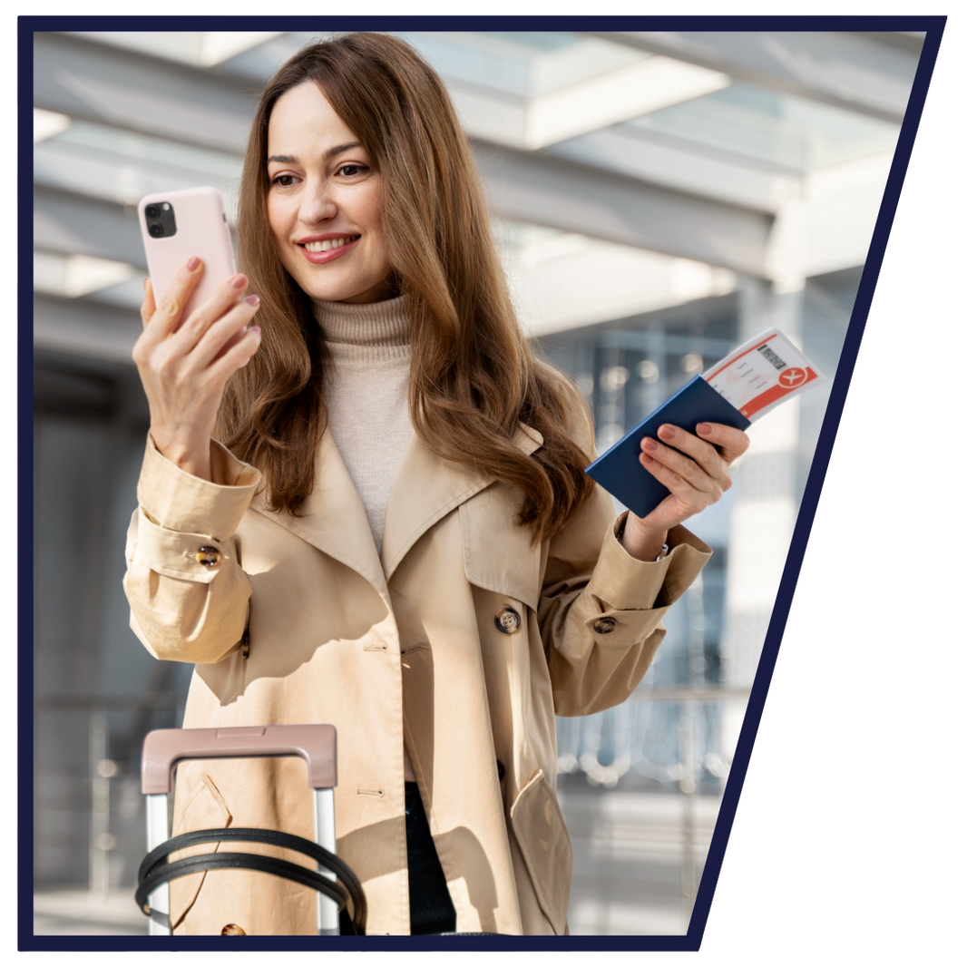 Woman in a beige coat holding a phone and passport in an indoor setting
